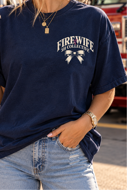 Woman wearing a vintage navy Fire wife graphic tee by 3H Collective, featuring a detailed firehouse, Dalmatian, pink heart, and “The Shift Ends. The Group Chat Begins.” back design.